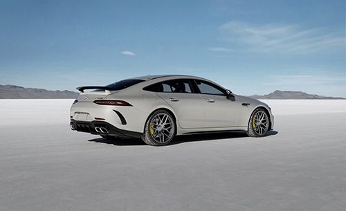 a gray sport car is on a plain near the water in the desert with blue sky